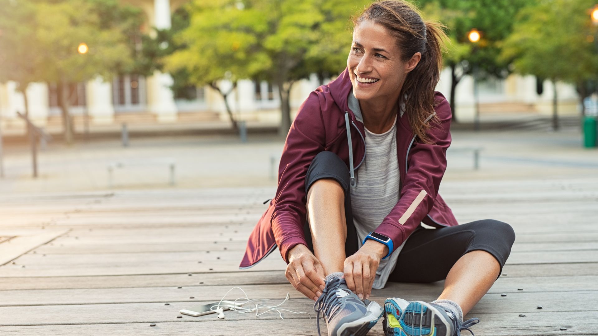 woman sitting down lacing up for run
