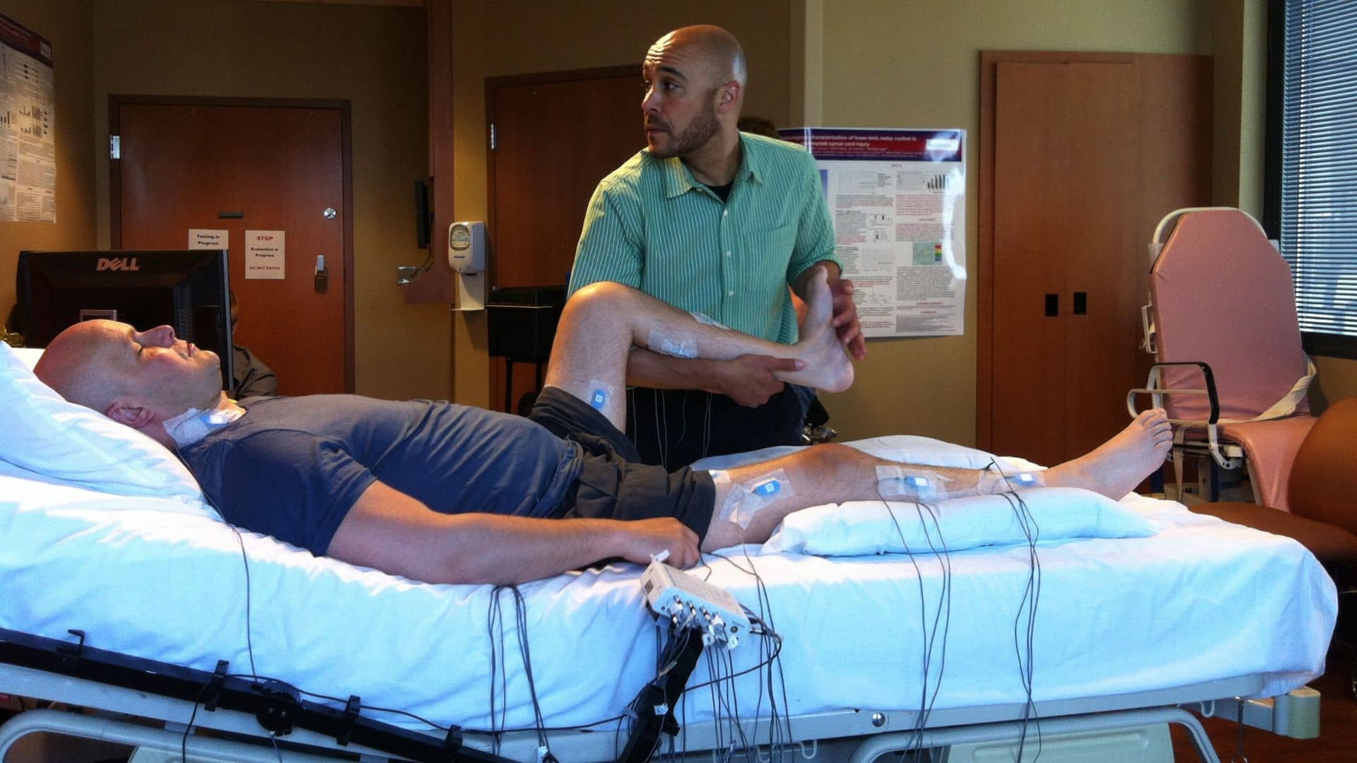 Mark Pollock in hospital bed with physiotherapist